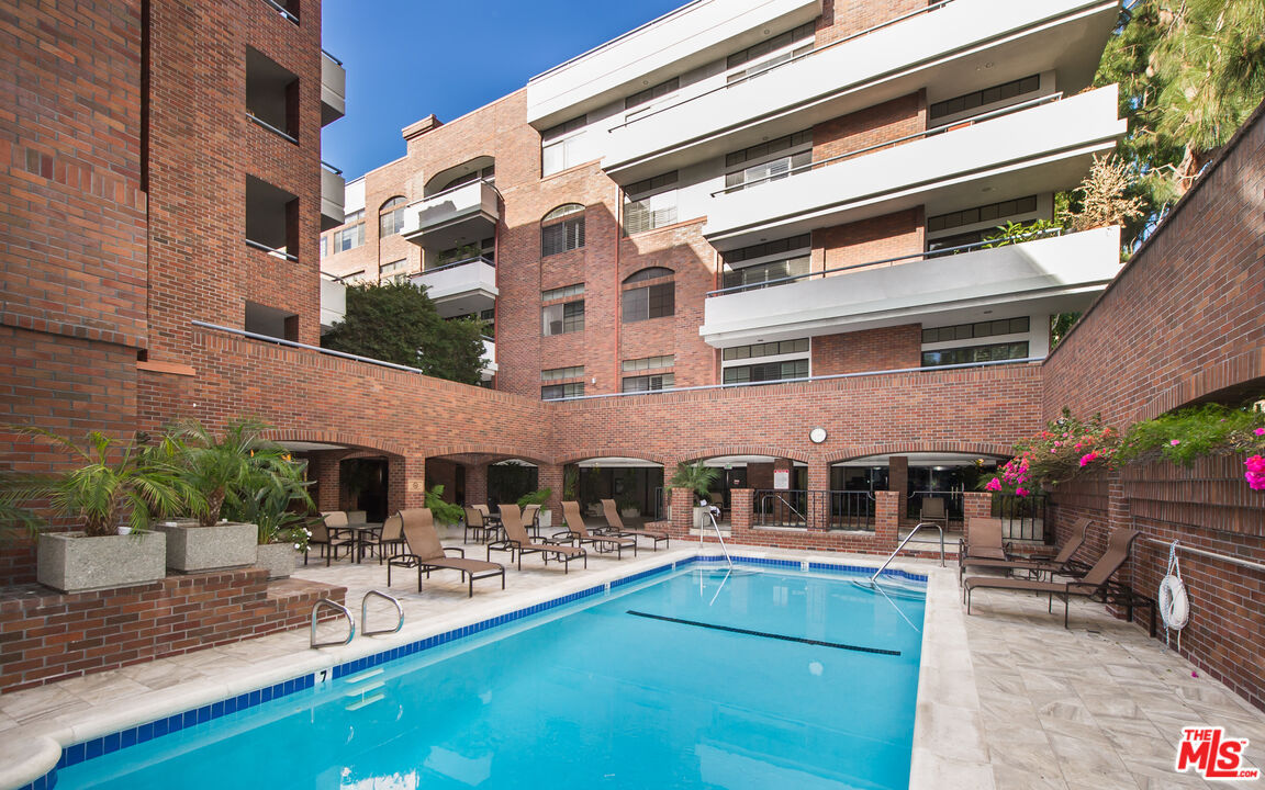The Somerset's heated pool courtyard with chaise lounges, brick arches and bougainvillea.